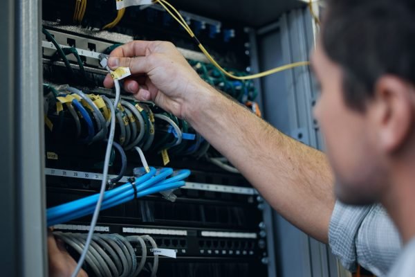 Server room, technician and hands of man with cable for programming, cybersecurity or maintenance. IT person in datacenter for network connection, software or system upgrade for internet or hardware.