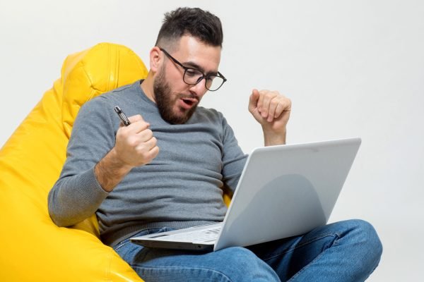 a guy rejoice while working on laptop